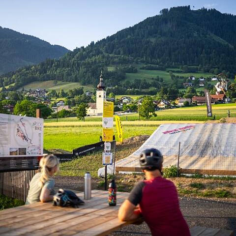 Mountainbiker bei einem Backflip-Sprung in den Bagjump Airbag in der Bike Area Obermillstatt vor Bergpanorama