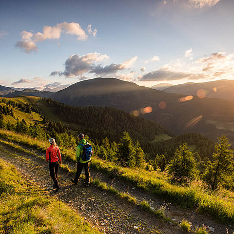Wanderer auf Etappe 4 des Nockberge Trail mit Panorama über die Nockberge Richtung Falkertsee im UNESCO Biosphärenpark.