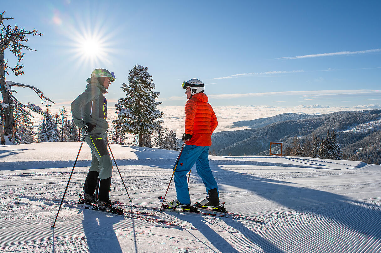 2 Skifahrer stehen auf der Piste im Sonnenschein