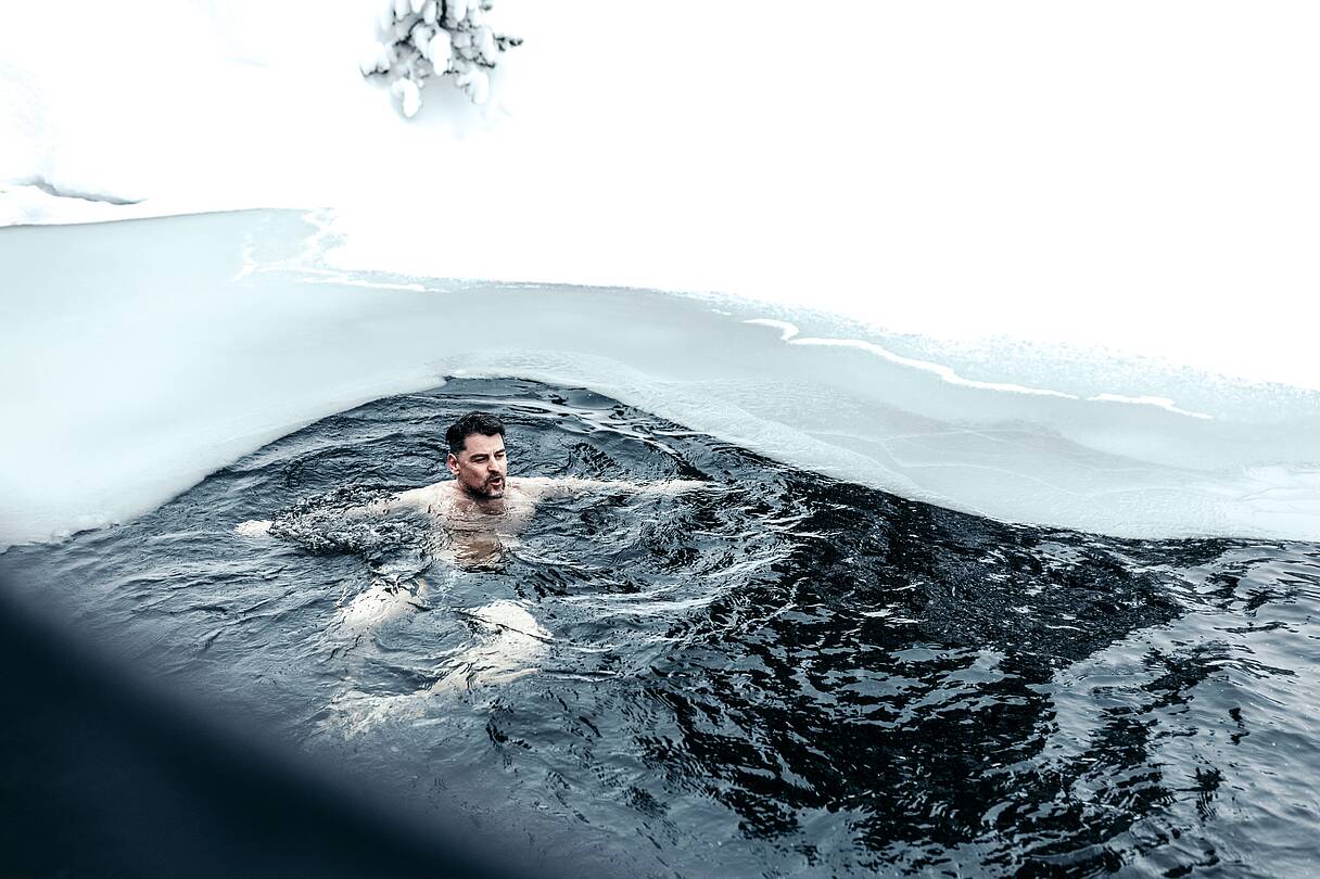 Mann schwimmt im teils zugefrorenen Turracher See