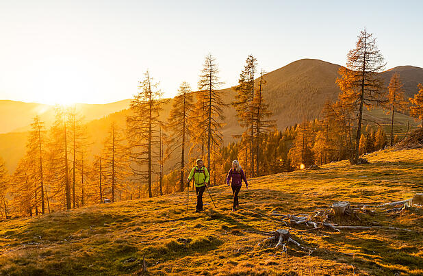 Wanderer bei Sonnenuntergang auf Etappe 7 des Nockberge Trail mit Ausblick Richtung Millstätter See im UNESCO Biosphärenpark.