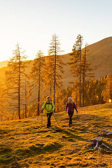Wanderer bei Sonnenuntergang auf Etappe 7 des Nockberge Trail mit Ausblick Richtung Millstätter See im UNESCO Biosphärenpark.