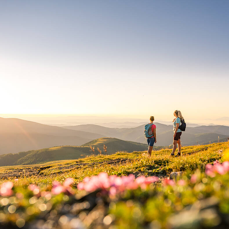 Zwei Wanderinnen auf Etappe 5 des Nockberge Trail oberhalb von Bad Kleinkirchheim mit Blick Richtung UNESCO Biosphärenpark.